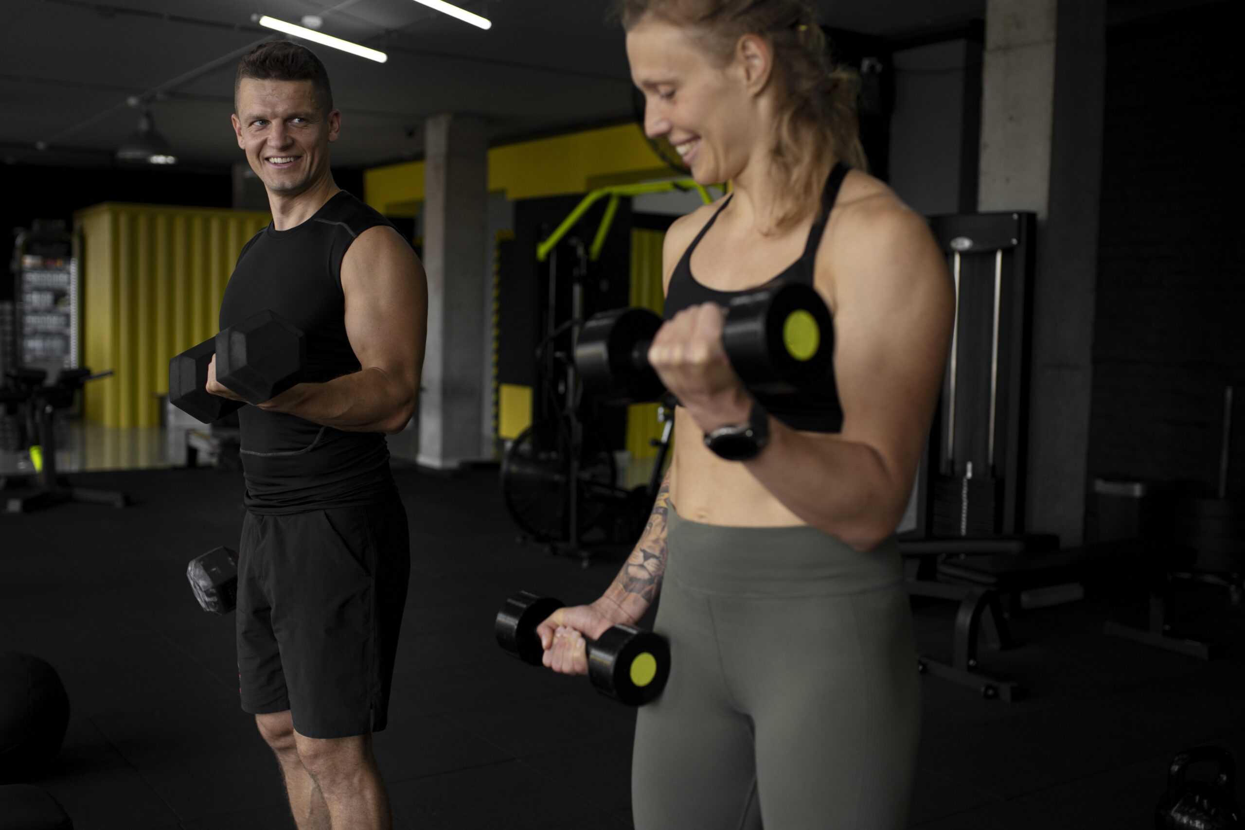 A male and female training with dumbbells in the gym