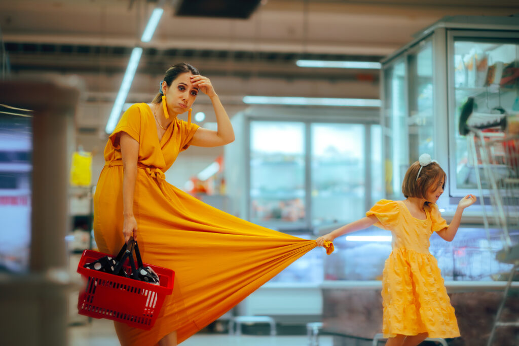 An exhausted mother in a yellow dress shopping in a supermarket with her child, illustrating the complex, emotional, and raw human reality that synthetic data fails to capture.