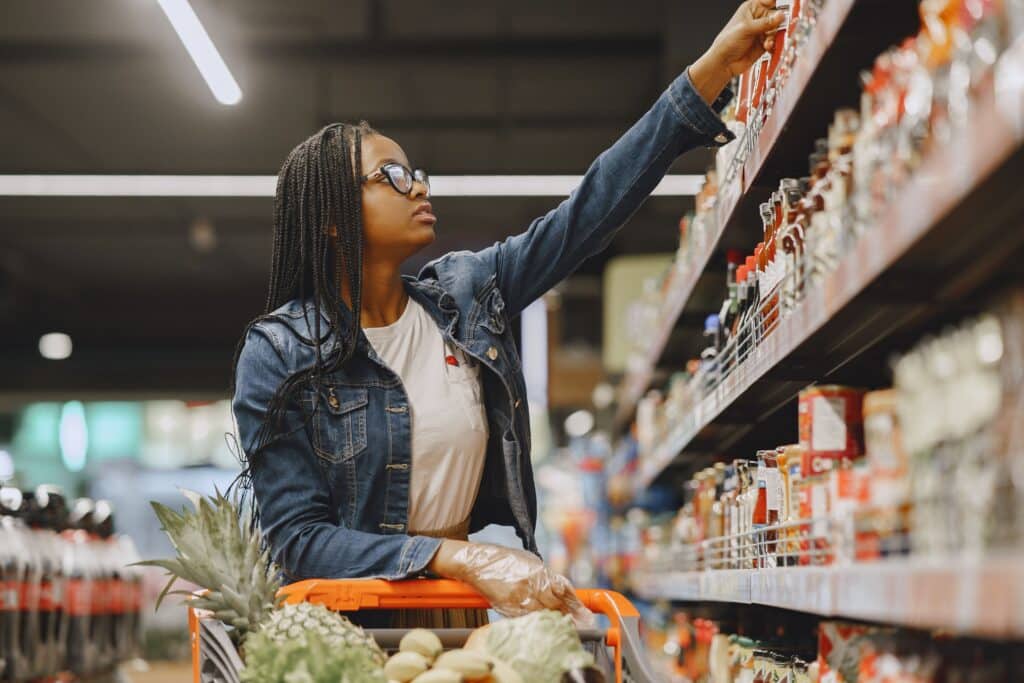 A shopper reaching for a product on a crowded retail shelf, demonstrating the importance of distinctive assets during a sustainable packaging revamp.