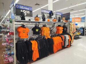 A retail clothing rack filled with Halloween t-shirts and pumpkin decorations, illustrating seasonal merchandising and UK shopper intent.