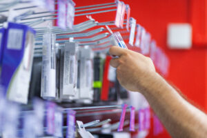 A shopper reaching out to physically touch and pick up a product on a retail display hook, demonstrating tactile interaction in store.