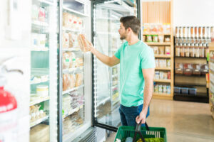 A shopper effortlessly selecting a product from a clean display fridge, demonstrating processing fluency and frictionless retail behaviour.