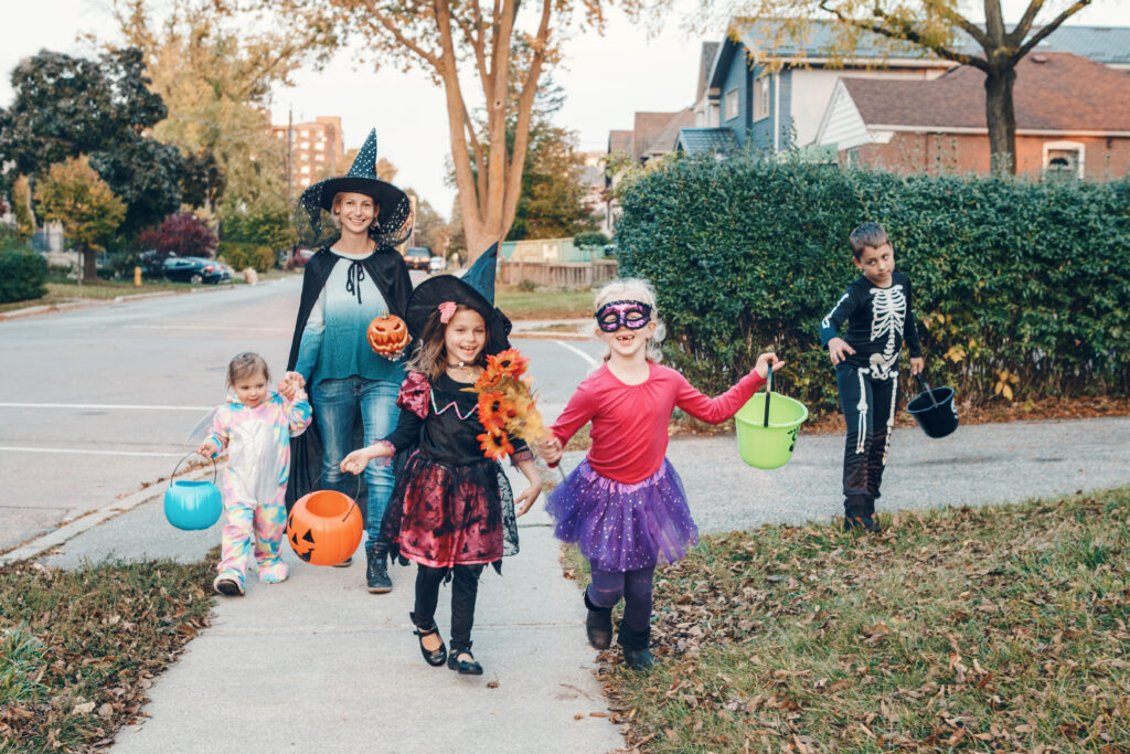 A family celebrating Halloween outdoors in full costumes, illustrating the return of social gatherings and seasonal consumer participation.