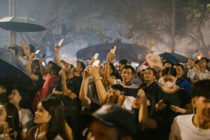 A crowd of attendees holding up smartphones at a live night event, illustrating digital engagement and hybrid festival experiences.
