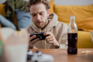 A person deeply engaged in playing a game on a mobile phone, illustrating the automatic habits and behavioural science behind free to play gaming.